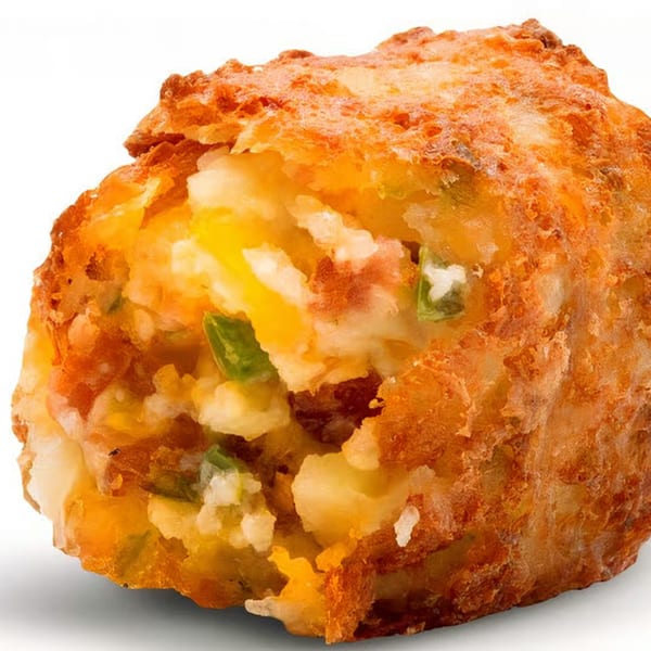 Close-up of a golden-brown fried potato and cheese bite with green specks.