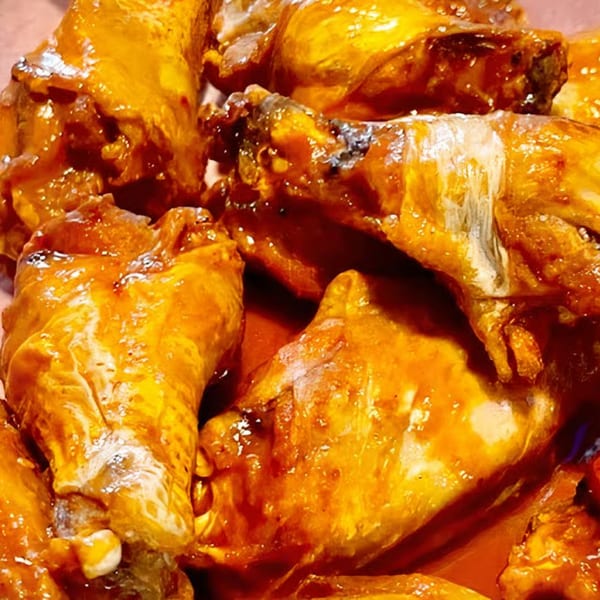 Close-up of Smitty's Bar's chicken wings, coated in a glistening orange-red sauce.